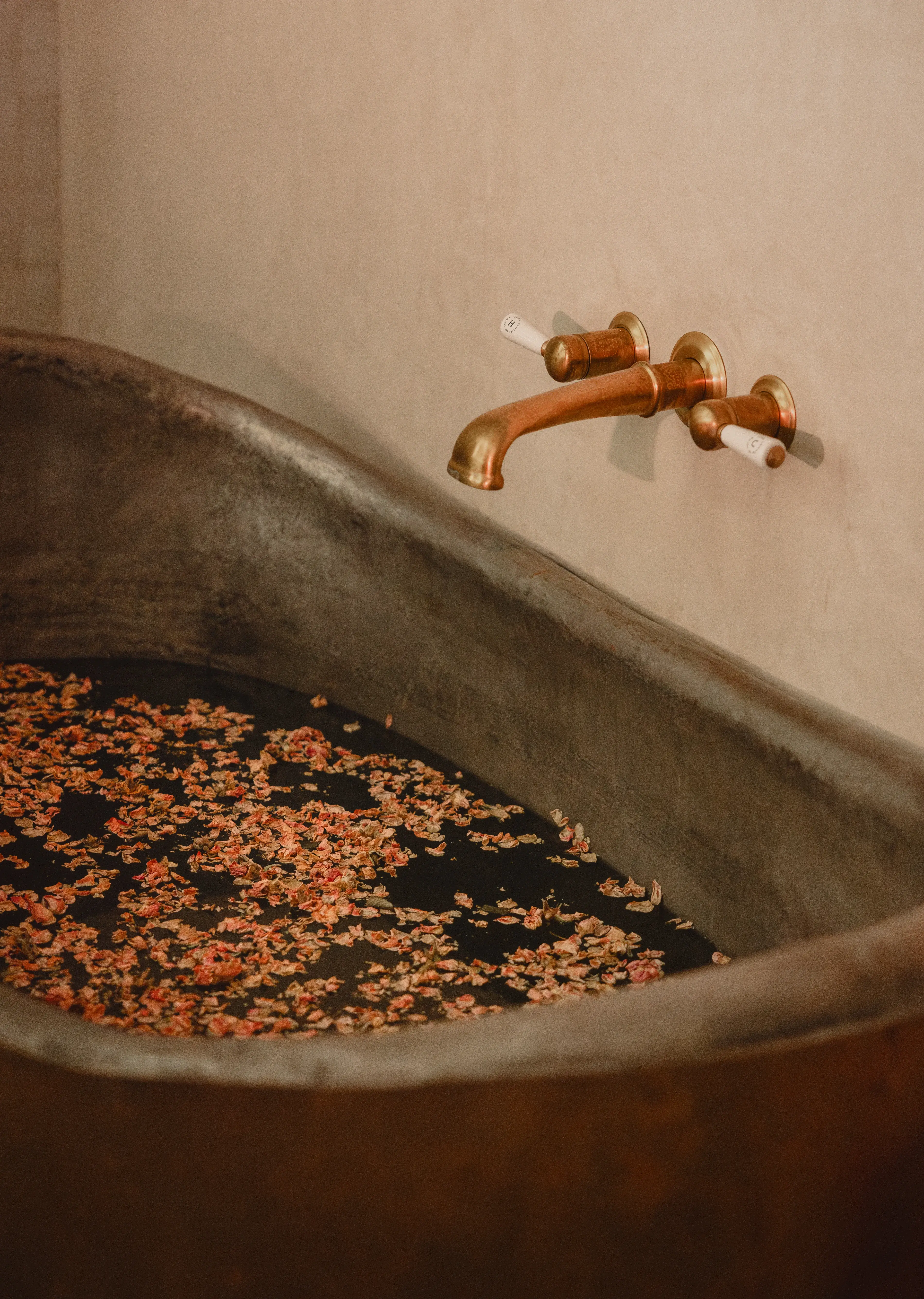 A copper bathtub with rose petals